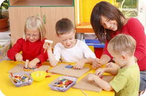 Children playing at the table with the teacher.